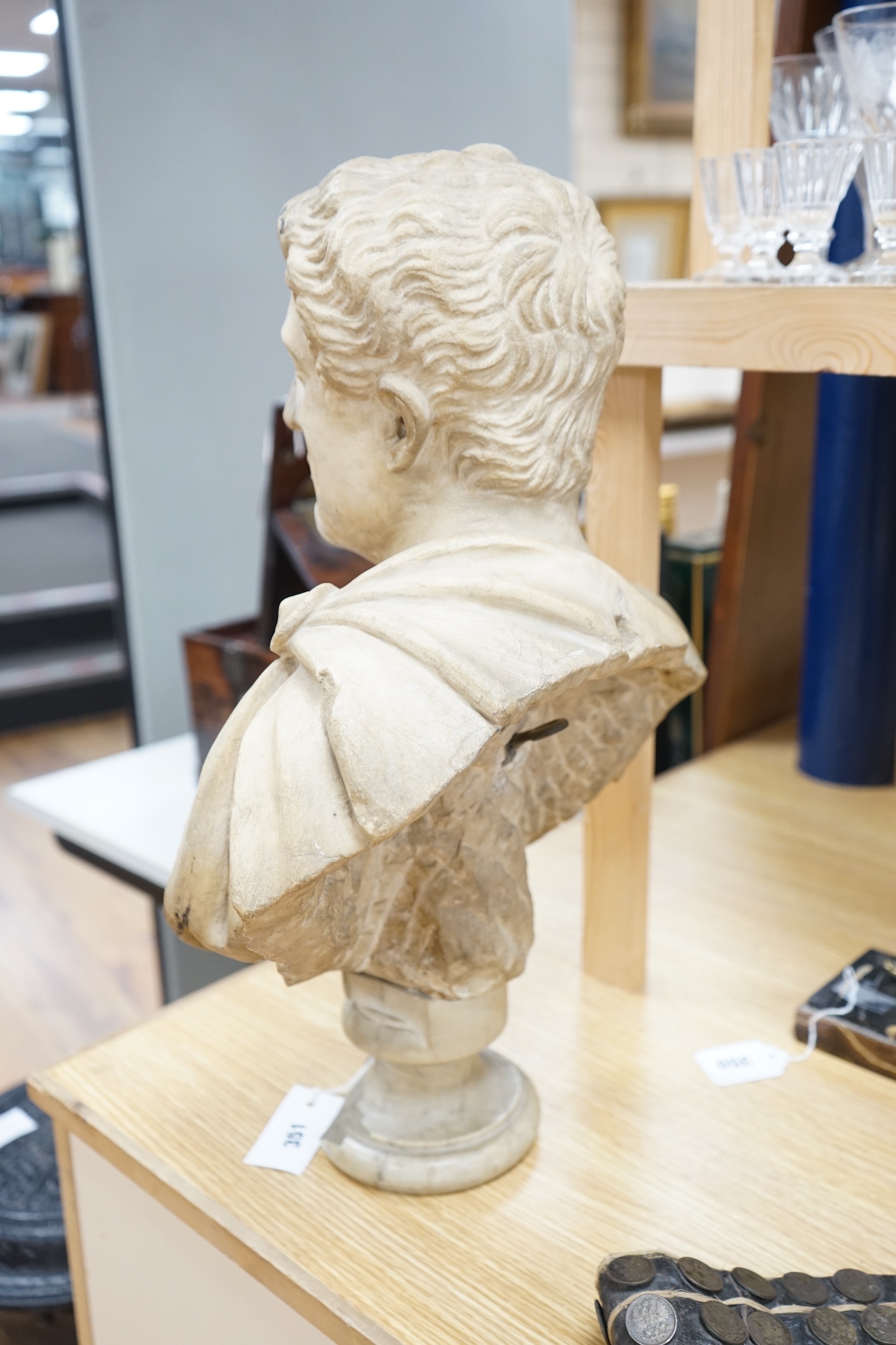 After the Antique marble bust of a Roman man wearing a Chlamys with a buckle at the shoulder, later socle and repairs, 54cm tall